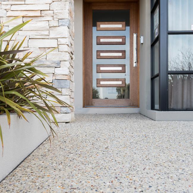 Exposed aggregate concrete in light beige colour leading to front door of house