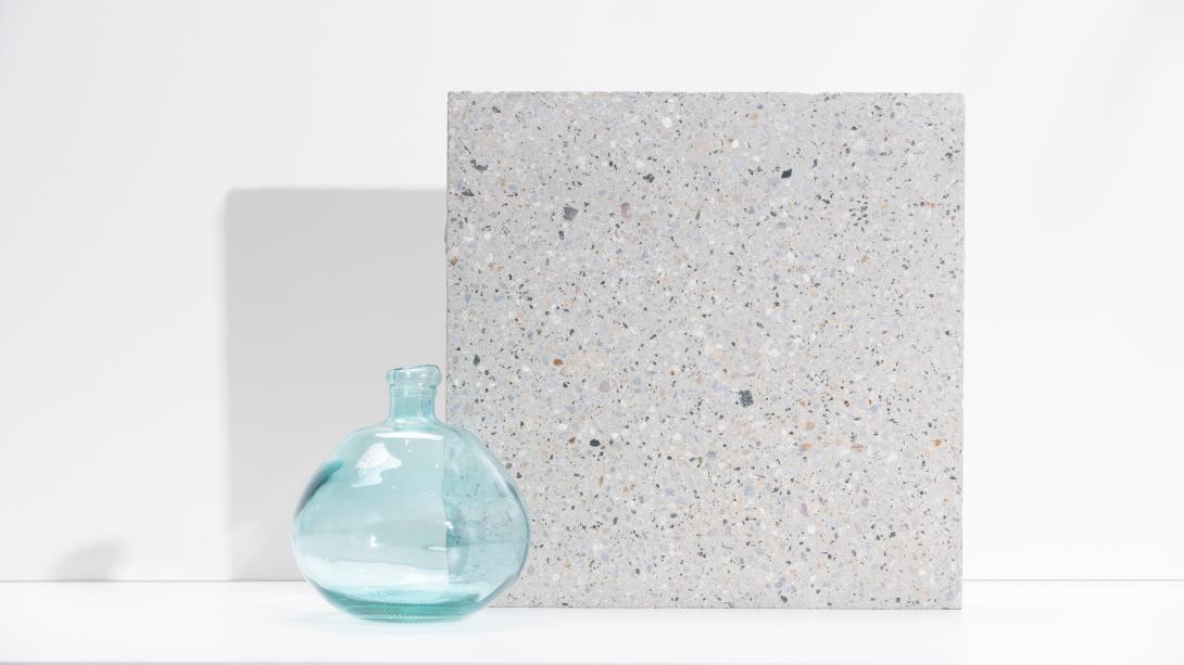 Slab of boralstone concrete in the colour Arctic Limestone next to a blue vase