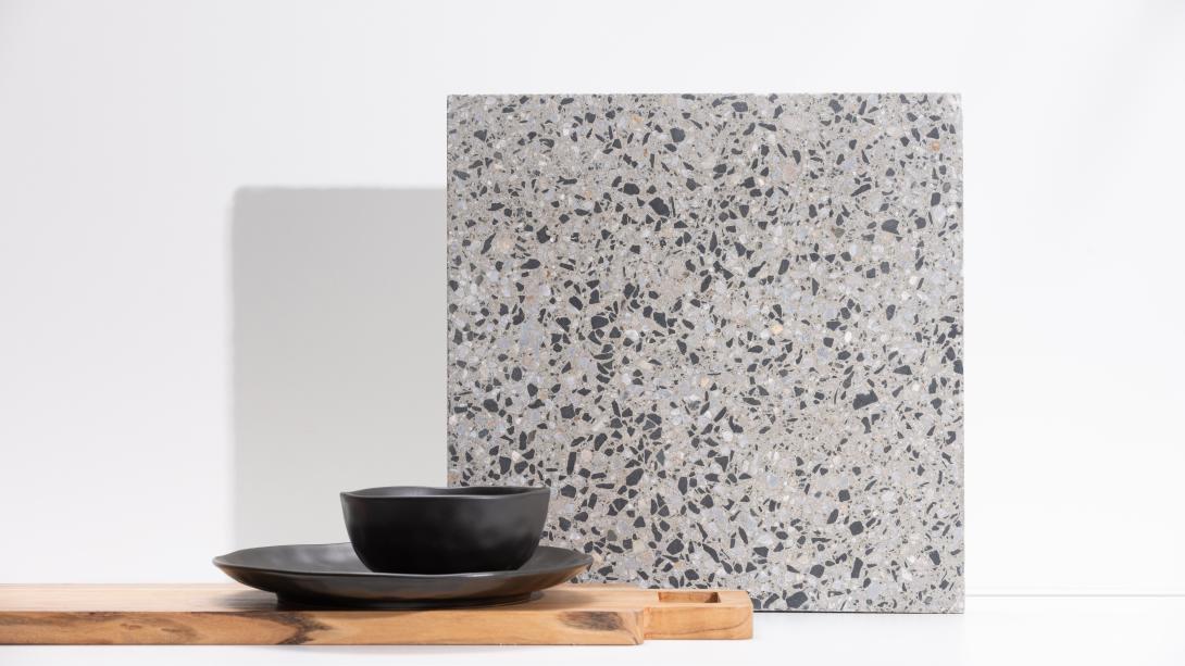 Slab of boralstone concrete in the colour Milkyway next to a black cup and saucer