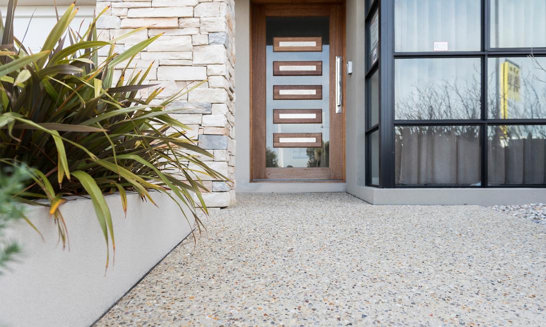 Exposed aggregate concrete in light beige colour leading to front door of house